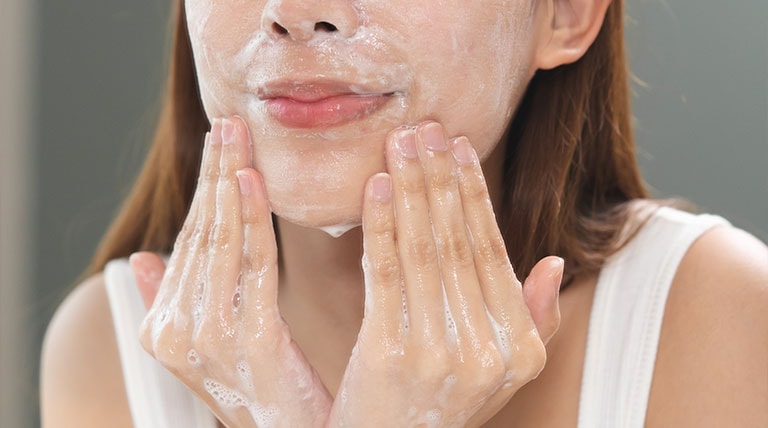 mulher de pele clara lavando o rosto